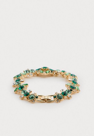 Kultainen rannekoru, jossa on vihreitä ja kirkaita jalokiviä aseteltuna kukkakuvioiksi vaalealla taustalla, ja siinä on lukko, jossa on merkintä "MARCHESA."