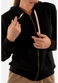 Giacca nera con cappuccio e zip frontale, dotata di cordini nei colori rosa e bianco e tasche frontali. Tessuto morbido con logo ricamato.