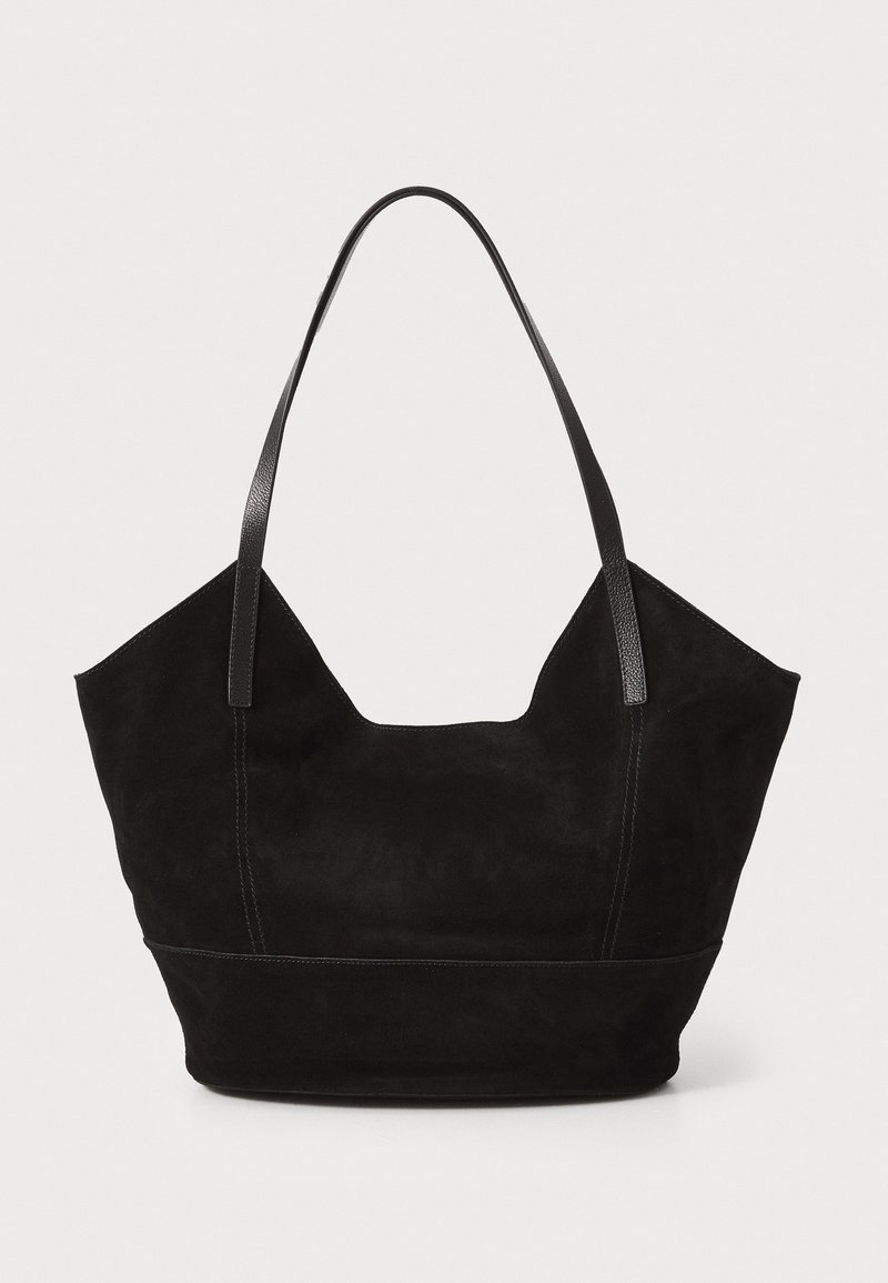 Sac fourre-tout en daim noir avec de longues poignées en cuir, forme arrondie, coutures apparentes et large ouverture. La texture est douce et mate.