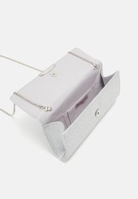 Hopeakimallella varustettu clutch-laukkumalli, jossa on ketjuhihna, napitus, sisätasku ja sileä kangaspäällyste. Avoin muotoilu paljastaa tilavan sisäosan.