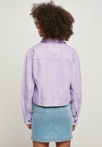 Lila denimjacka med en kortad design och knäppta manschetter, i kombination med en ljusblå denimkjol med bakfickor.