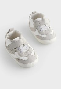 Baskets pour tout-petits grises et blanches avec une sangle velcro, des accents en suede texturé et une semelle en caoutchouc avec une traction à motifs.