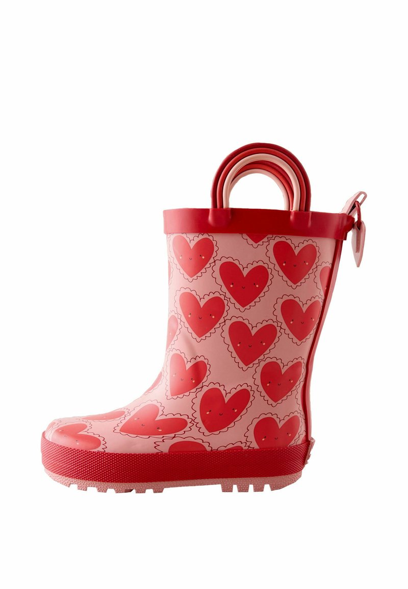 Pinker Gummiregenstiefel mit einem roten Herzmuster, strukturierter Sohle und rotem Rand. Oben befinden sich zwei Griffe für einfaches An- und Ausziehen.