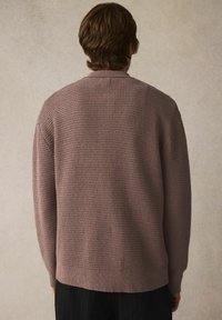 Pleteni kardigan u umirujućoj mauve boji, s teksturiranim uzorkom, rebrastim manžetama i ravnim rubom. Stražnji pogled prikazuje visok ovratnik i opušteni kroj.