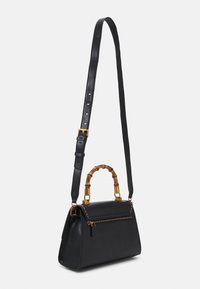 Sort læderhåndtaske med en struktureret form, guldfarvede metaldele, bambushåndtag og en justerbar rem. Har en lynlåslomme.