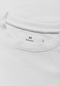 Balta medvilninė marškinėliai su apvaliu iškirpimu. Etiketėje užrašas "Matinique" su "M" logotipu ir dydžiu "L", prisegta viduje prie apykaklės.