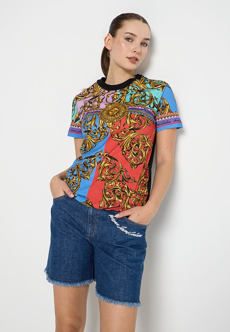 Koszulka graficzna w wielu kolorach z ozdobnymi złotymi wzorami, krótkie rękawy i czarny okrągły dekolt, w zestawie z dżinsowymi szortami z frędzlami.