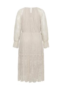 Robe longue en dentelle crème avec manches évêques transparentes, taille cintrée, poignets froncés et ouverture en forme de goutte d'eau dans le dos.