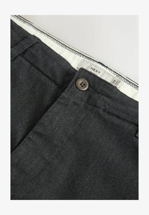 Dark gray trousers with a textured fabric, featuring a button closure and waistband label. Includes subtle stitching details along the edges.