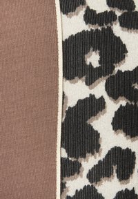 Textil mit zwei Abschnitten: einem einfarbigen, braunen, gerippten Stoff und einem weißen Untergrund mit schwarzem Leopardenmuster, getrennt durch einen cremfarbenen Rand.