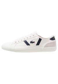 Valkoiset kangaskengät, joissa on laivaston sinisiä yksityiskohtia. Sivussa logo, pyöreä kärki, kumipohja ja nauhakiristys. Pehmeä mokkahiena. 