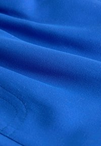 Tissu bleu avec une texture lisse, présentant de douces plis et coutures, mettant en valeur sa couleur vibrante et son fini doux.