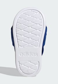 Suela de zapato Adidas con base de goma blanca, que presenta un patrón de agarre texturizado y branding en relieve. Parte superior azul visible en los bordes.