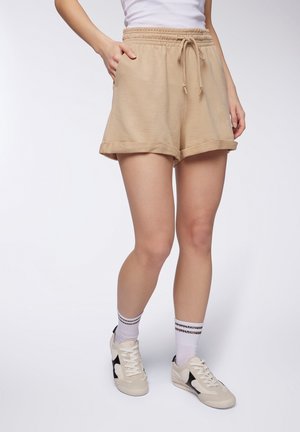 Pantaloni corti in cotone beige con una cintura elastica e lacci regolabili. Presenta tasche laterali e orlo arrotolato. Abbinati a sneaker.