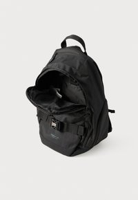 Zaino nero realizzato in tessuto resistente, dotato di chiusura con zip, spallacci regolabili e una cintura frontale. L'interno è spazioso e foderato.