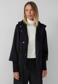 Schwarzer Wollmischmantel mit breitem Kragen, Knopfverschluss und zwei vorderen Taschen. Verfügt über gerippte Bündchen und ein lässiges Design.