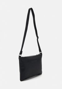 Zwart crossbody tasje gemaakt van soepel leer met een ritsluiting, verstelbare schouderriem en subtiele stiksel details aan de voorkant.
