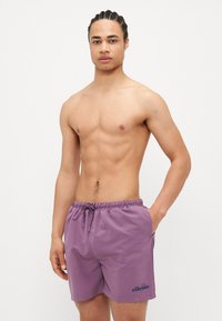 Μωβ κοντά μαγιό φτιαγμένα από ελαφρύ ύφασμα, με ελαστική μέση και κορδόνι, πλαϊνές τσέπες και λογότυπο στο στρίφωμα.