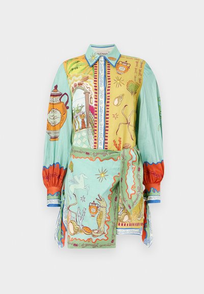 Φανέλα σε ζωηρά χρώματα με περίπλοκα σχέδια σε κίτρινο και πράσινο, με λεπτομερείς απεικονίσεις, μακριά μανίκια και γιακά.