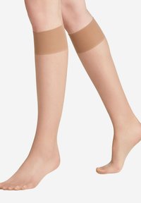 Beige knielange kousen met een gladde, doorzichtige afwerking en elastische bovenrand, die een naadloos ontwerp en een lichte textuur benadrukken.