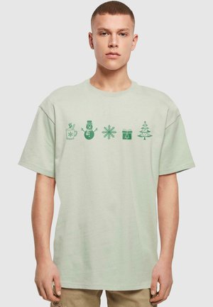 Lys grøn bomulds t-shirt med korte ærmer, der har ferietema grafik: en krus, snemand, snefnug, gave og træ i mørkegrøn.