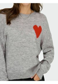 Maglione grigio a maglia con un cuore rosso ricamato sul lato sinistro del petto. Il design include polsini e orlo a coste, con una texture morbida.