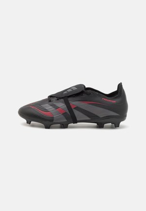 Crampons de football Adidas Predator noirs et gris avec accents rouges, empeigne texturée, couvre-lacets et crampons moulés sur fond blanc.