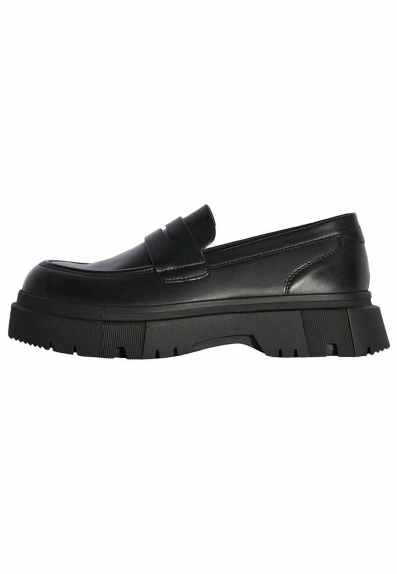 Mocassin en cuir noir avec une semelle épaisse en caoutchouc à crampons et une large bride sur le dessus, présenté de profil sur fond blanc.