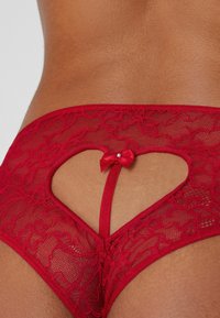 Rote Spitzenunterwäsche mit herzförmigem Ausschnitt am Rücken, versehen mit einer Satin-Schleife und zarten Blumenmustern.