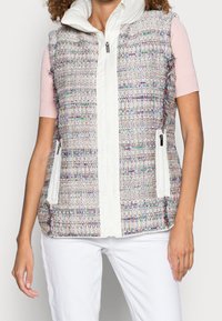 Chaleco acolchado de tejido texturizado multicolor, con un cierre frontal blanco, dos bolsillos frontales con cremalleras y cuello alto.