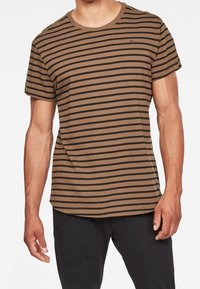 Camiseta de rayas marrones con mangas cortas, escote redondo y una textura suave. Las rayas oscuras contrastan con la base marrón más clara.