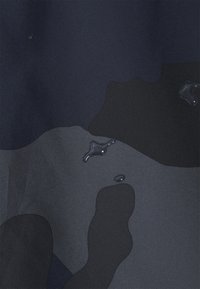 Texturerat tyg i olika nyanser av mörkblått och grått med en slät yta, med subtila vattendroppar på ytan.