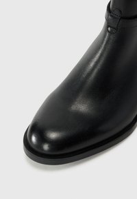 Černé kožené kotníkové boty s hladkým povrchem, kulatou špičkou a minimalistickými prvky. Vyznačují se elegantním siluetou a robustní černou podrážkou.