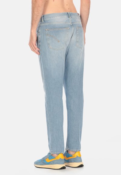 Jeans in denim azzurro con taglio dritto, cinque tasche e dettagli di cucitura sottili. Abbinati a sneaker blu e gialle.
