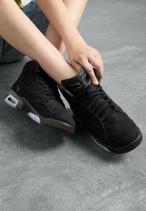 Scarpe sneakers alte nere con texture in suede e pelle, dotate di una suola spessa, perforazioni e accenti minimalisti.