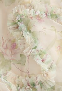 Permatomas audinys su švelniais rožinės ir žalios spalvų gėlės raštais, su subtilia raukšlėta apdaila, atitinkančia spalvas.