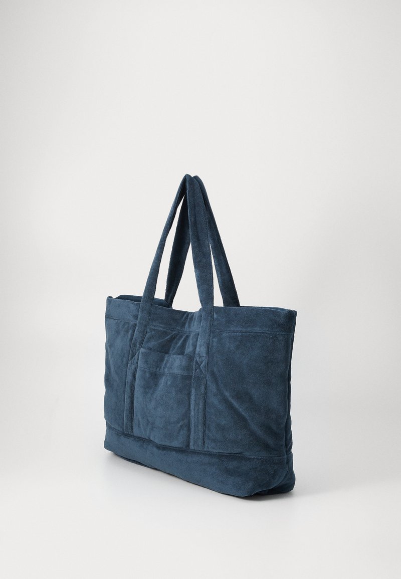 Tasche aus navyblauem Stoff mit zwei Griffen, strukturierter Oberfläche, zwei Vordertaschen und einem geräumigen Hauptfach.