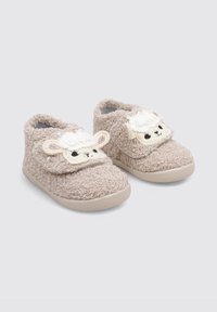 Zapatos de bebé beige y peludos con un exterior suave y texturizado, que presentan un detalle de cara de oveja color crema, cinta de velcro y suela de goma.
