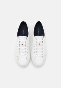 Sneakers bianchi in pelle con punta arrotondata, lacci piatti bianchi, soletta blu e piccolo logo sul lato. Texture liscia e design classico.