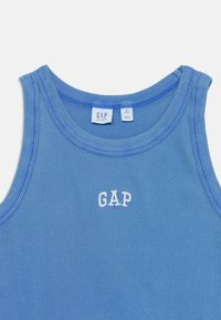 Mėlynas dryžuotas liemenėlei su apvali kaklo iškirpte, puošia balta išsiuvinėta "GAP" logotipas. Prietaisas rodo dydį XL, skirtas vaikams.