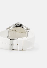 Orologio con cinturino in silicone bianco, caratterizzato da una cassa in acciaio inossidabile, un retro lucido e una corona per la regolazione dell'ora. Inclusa chiusura a fibbia.