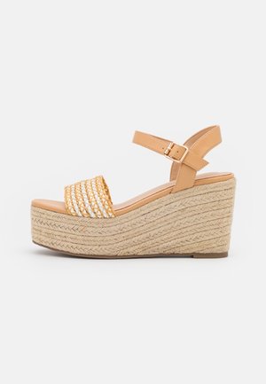 Kile sandal med flettet jutebund, tanfarvet læderankelrem med spænde og åben tå med flettet tan- og hvidt materiale.
