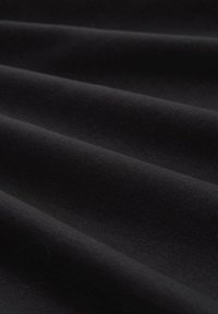 Tessuto nero drappeggiato in onde, mostrando una texture liscia e una leggera lucentezza. Il materiale appare leggero e strettamente tessuto.