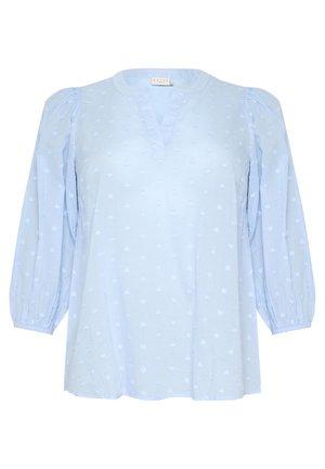 Blouse bleu clair avec un col en V, des manches bouffantes et des détails brodés en forme de cœur. Fabriquée dans un tissu doux et texturé.