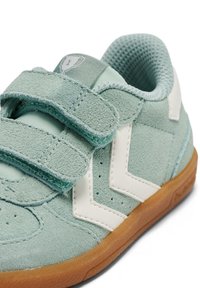 Jasnoniebieski zamszowy but z dwoma paskami na rzepy, białe akcenty w kształcie zygzaka oraz gumowa podeszwa. Cholewka o fakturze oraz oddychająca siateczkowa wyściółka.