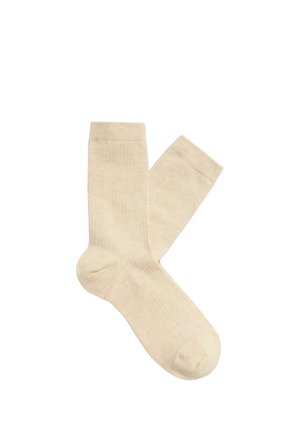 Paire de chaussettes montantes beiges unies avec bord-côte et motif tricoté vertical subtil, posées à plat sur fond blanc.