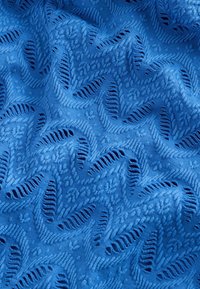 Blauwe stof met een gestructureerd bladvormpatroon en uitsparingen, wat een golvend ontwerp creëert. Gladde textuur met een levendige, effen kleur.