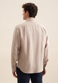 Lichtbeige langemouwen shirt met een relaxte pasvorm, achterkant plooien, knoopmanchetten en een klassieke kraag, gemaakt van een geëtst stof.