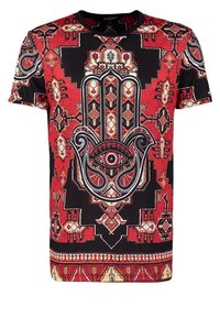 T-shirt à manches courtes rouge et noir avec des motifs géométriques et floraux complexes. Le design central comprend un motif de main et un détail d'œil.