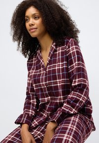 Μαρόνο καρό σετ πιτζάμας φτιαγμένο από μαλακό ύφασμα, με πουκάμισο με γιακά και μακριά μανίκια σε χαλαρή γραμμή και ταιριαστά παντελόνια.